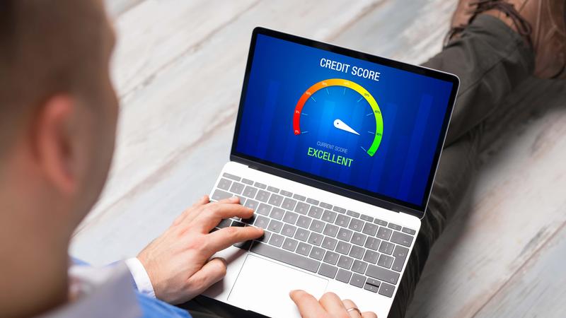 Man looking at his credit score test on laptop showing excellent score