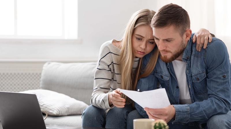 Upset couple reading financial statement from bank at home