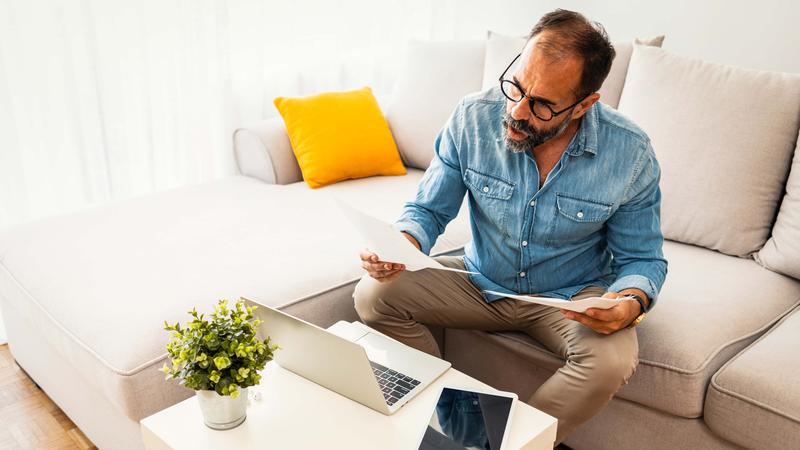 Upset frustrated mature man reading document sit at home table