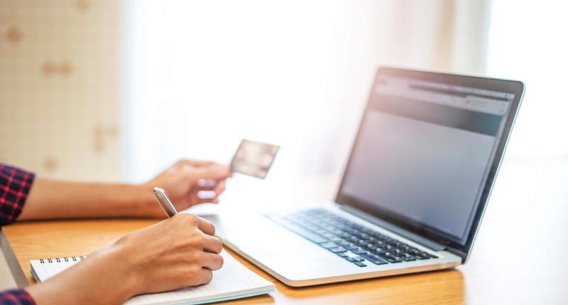 closeup of hands with a laptop computer using credit card and entering billing information on the purchasing