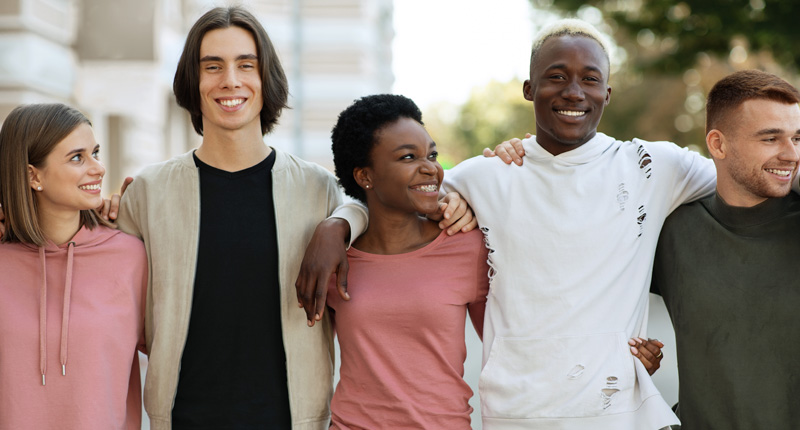 international group of students hugging while standing on the street